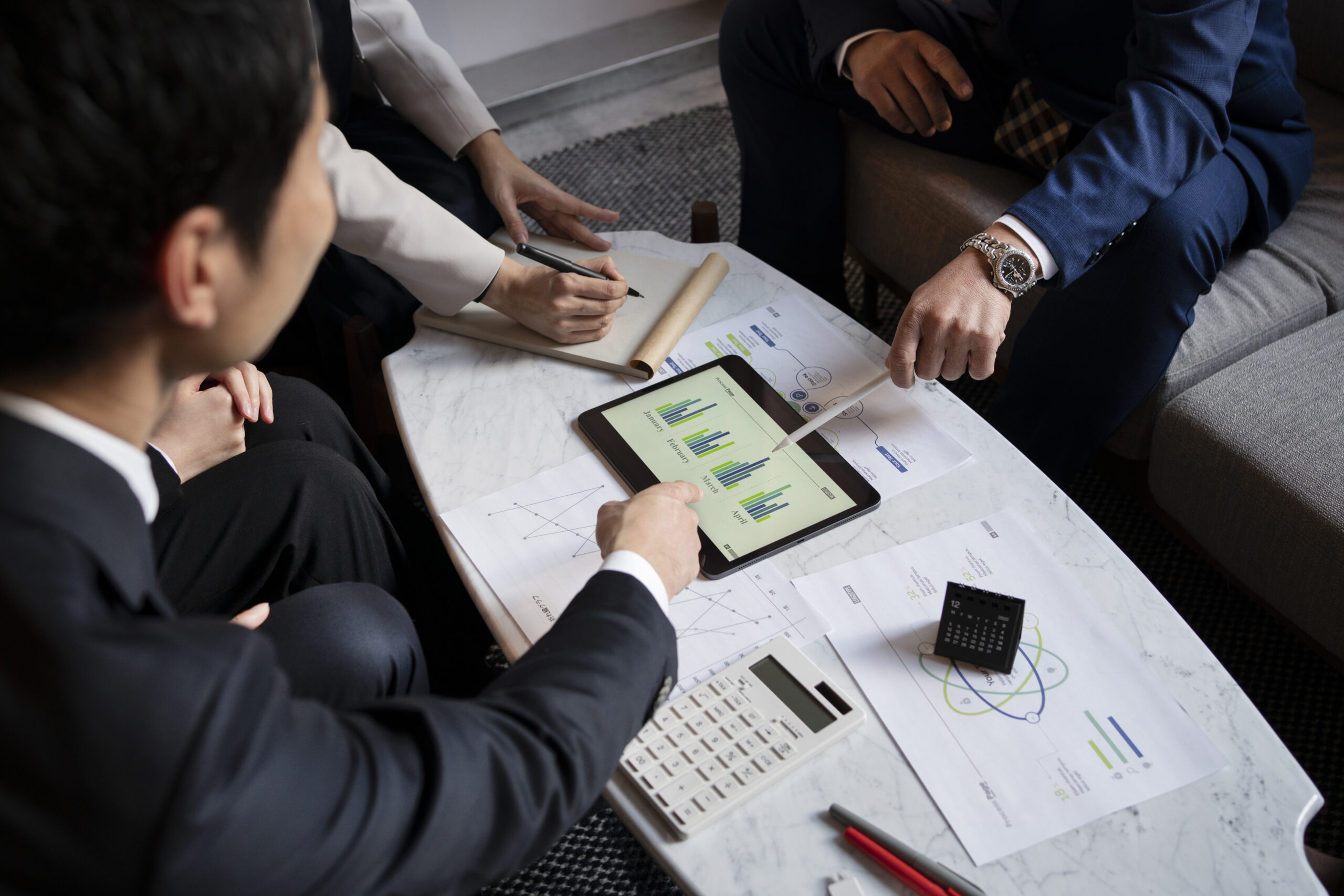 Financial professionals reviewing investment documents and analyzing portfolio data on a tablet, representing the qualified purchaser verification process for Private Placement Life Insurance (PPLI) eligibility.