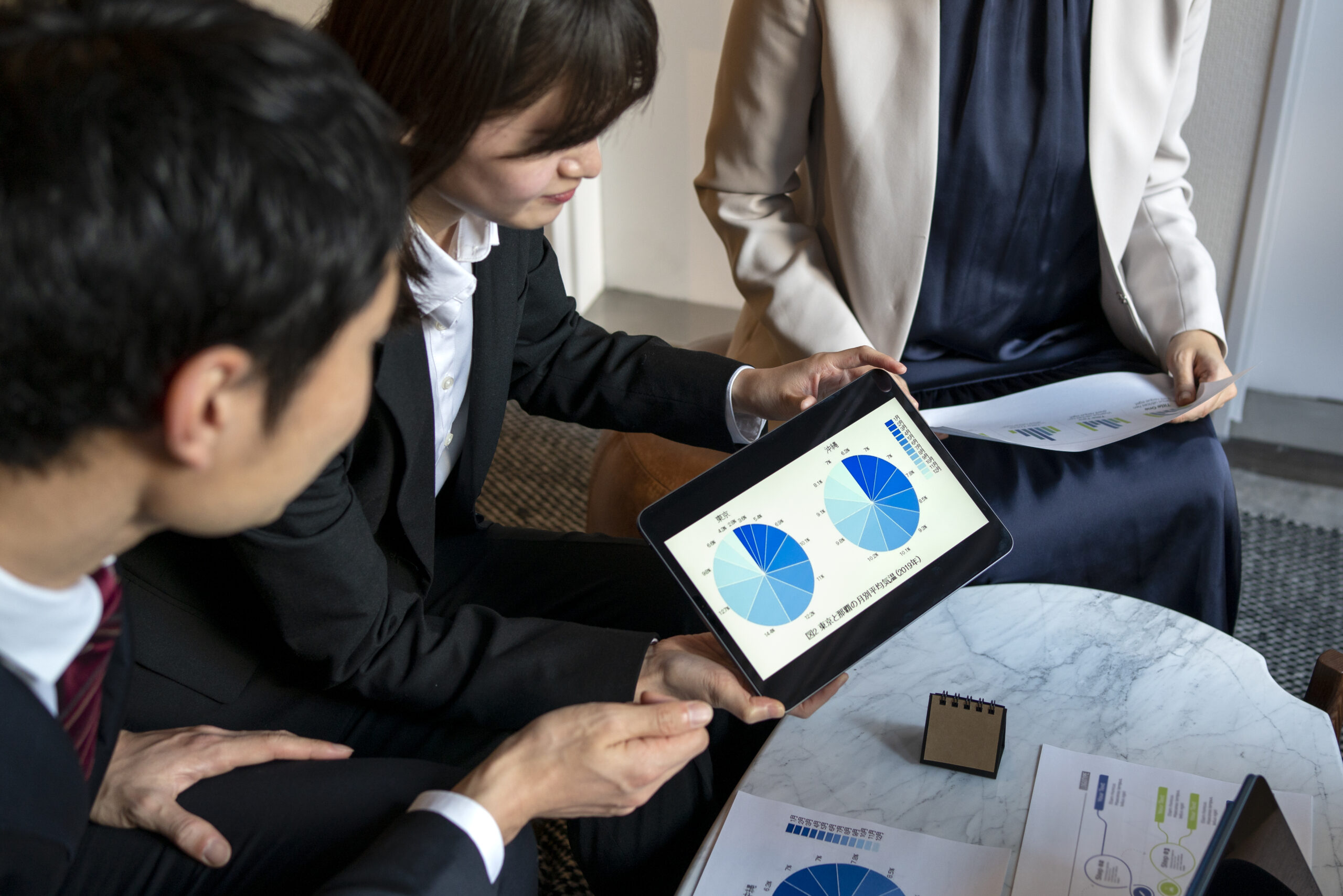 Financial advisors reviewing asset allocation pie charts on tablet during PPLI investment policy statement planning meeting